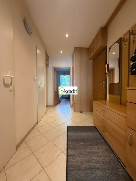 A hallway in a 3-room apartment with tiles and wooden furniture.