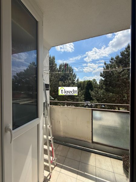 The balcony of a 3-room apartment in Zlaté Moravce with a view of greenery and the sky.