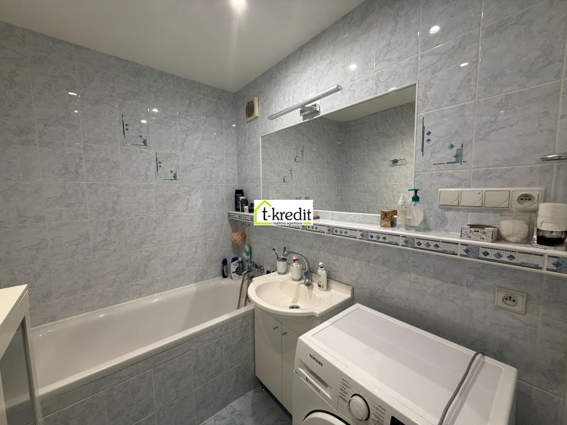 Bathroom in a 3-room apartment with a bathtub and a washing machine, bright tiles.