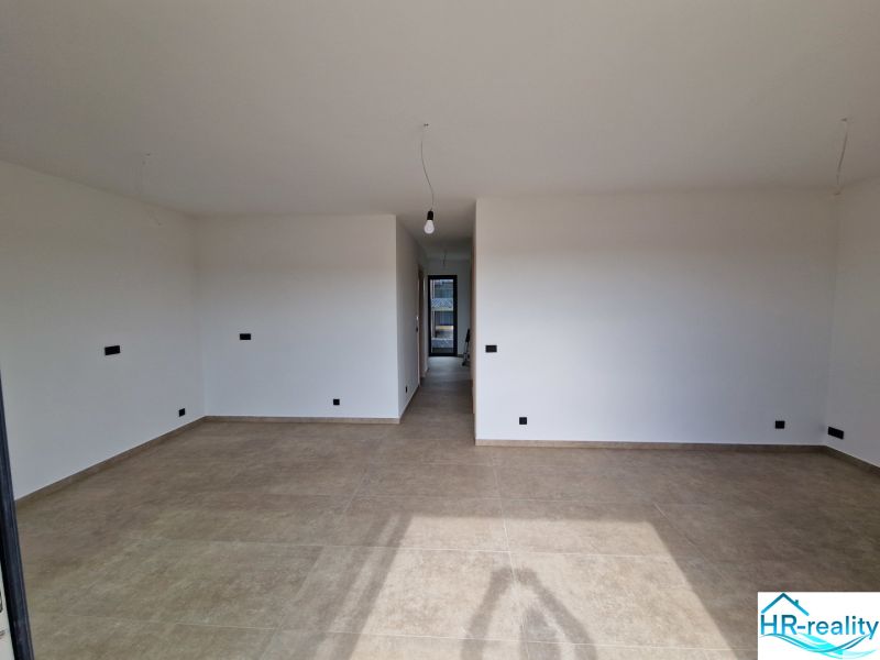 Interior of a holiday apartment with large white walls and a wooden decor floor.