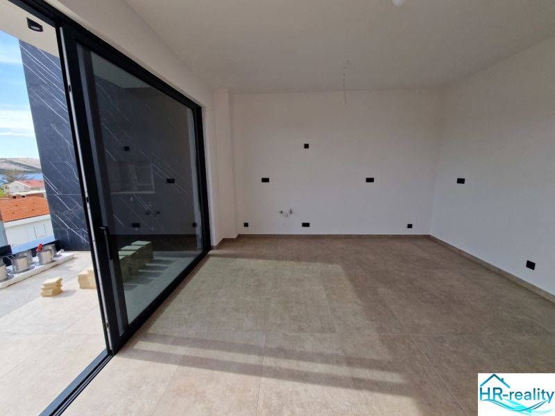 Interior of a holiday apartment with large glass doors and tiled floor.