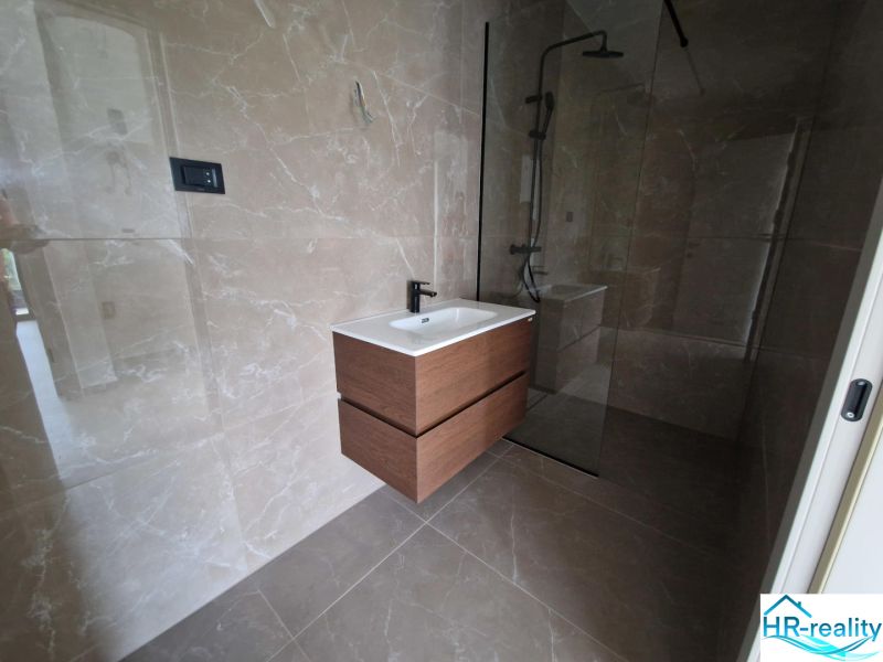 A bathroom in a holiday apartment with ceramic tiles and a shower enclosure.