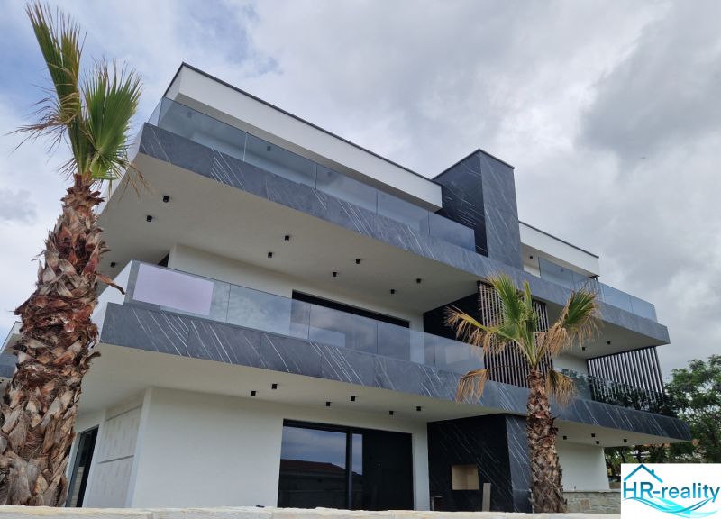 A recreational apartment in Stara Novalja with geometric architecture and palm trees against the backdrop of the sky.