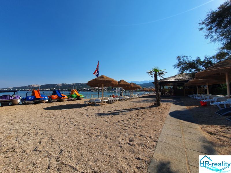 A beach with sunbeds and pedal boats in Stara Novalja near a holiday apartment.