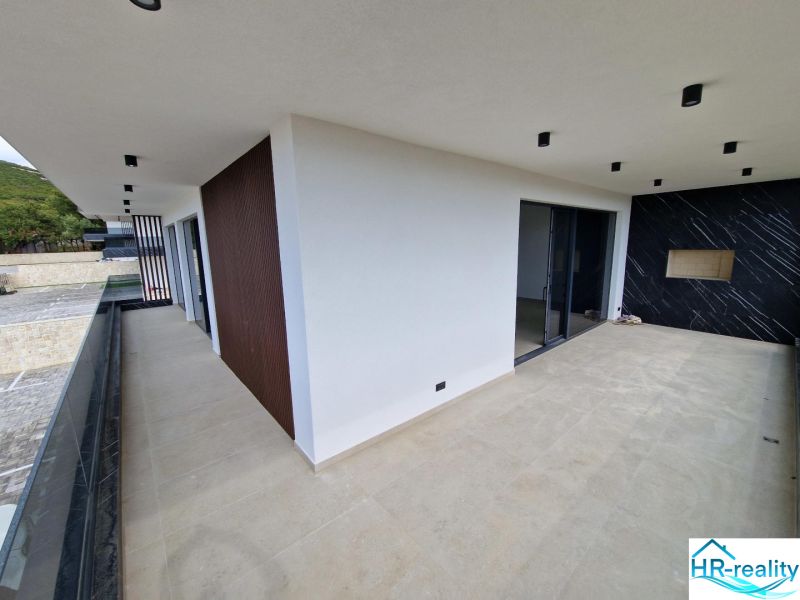 Terrace of a recreational apartment in Stara Novalja with ceramic tiles and a view of greenery.