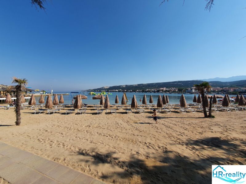 A sandy beach with umbrellas and loungers at a holiday apartment in Stara Novalja.