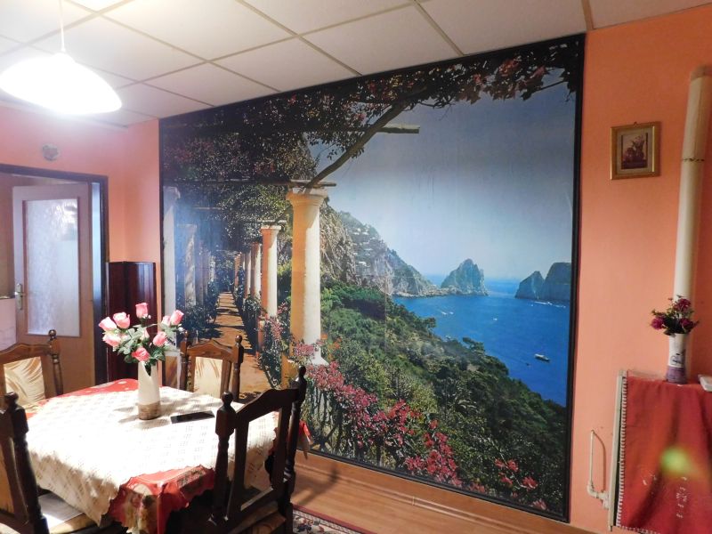 A dining room in a family house decorated with a wall mural featuring a seaside motif and wooden decor.