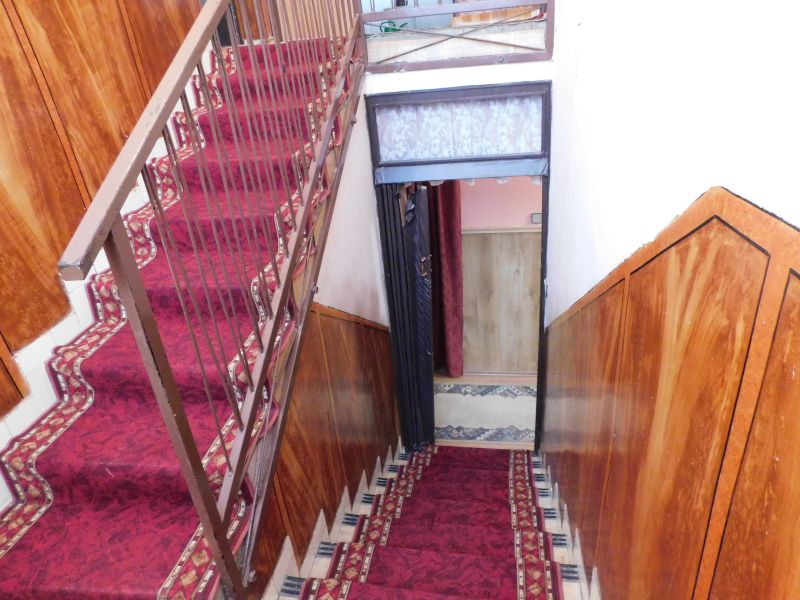 A hallway in a family house with a red carpet and walls with wooden decor.