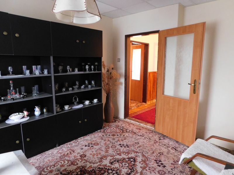 Living room of a family house with a dark cabinet, decorative glasses, and open doors.