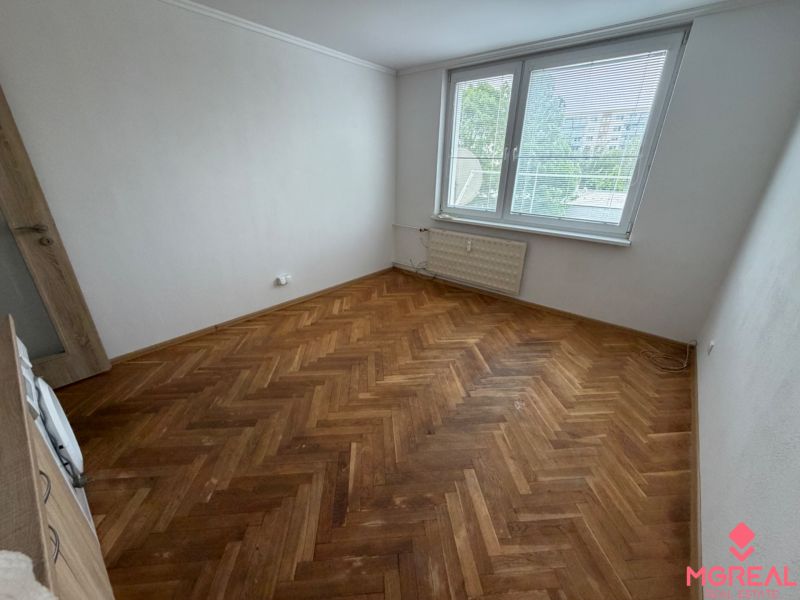 A studio apartment with a wooden decor floor and a large window.