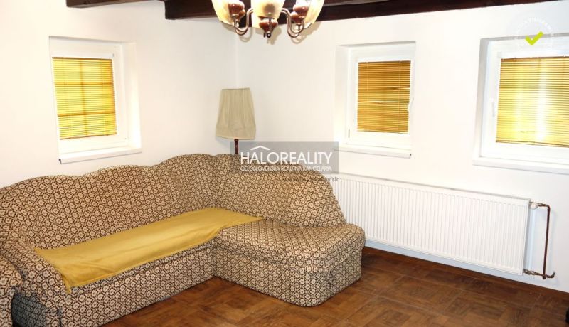 Living room with a retro sofa, lamp, and wooden decor flooring in a family house.