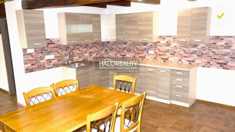 A kitchen in a family house with a wooden decor floor and brick cladding.