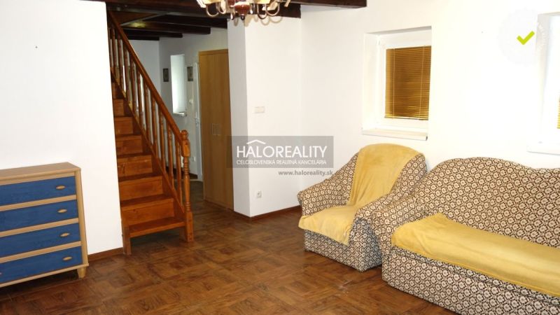 A room in a family house with a staircase, chairs, and a floor with a wooden decor.
