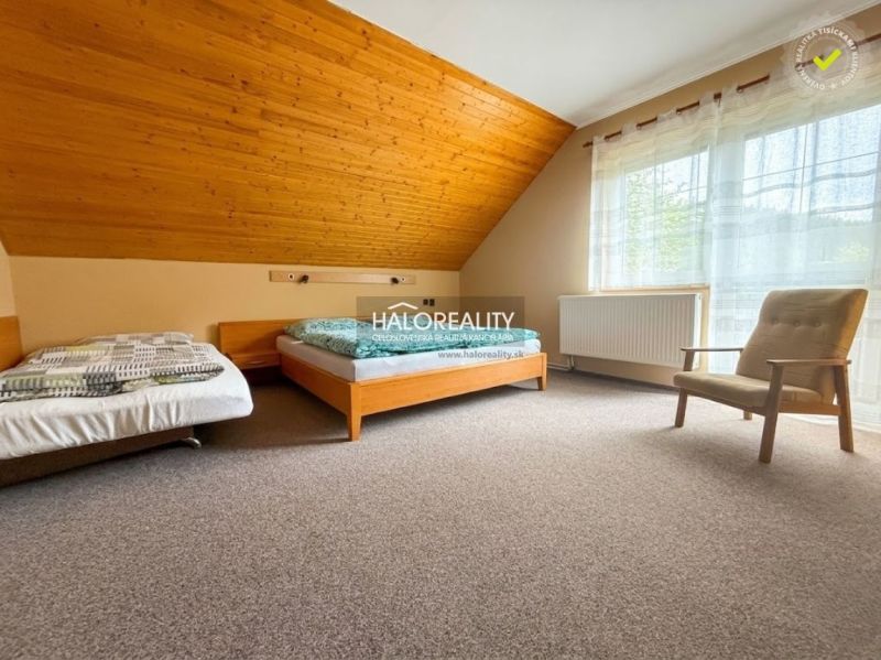 A room with two beds, an armchair, and a floor with a wooden decor in hotels and guesthouses.