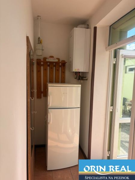 Kitchen in a studio apartment with a refrigerator, gas boiler, and coat rack.
