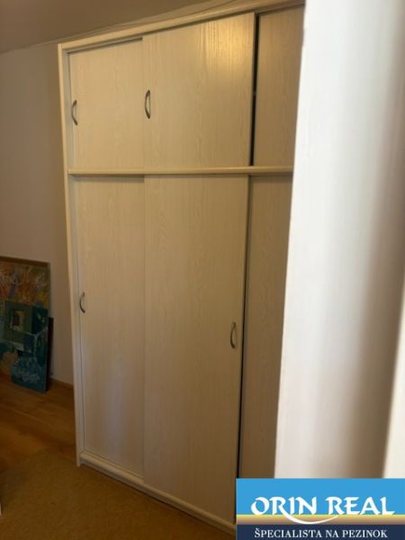 A wardrobe with doors in a studio apartment on a floor with a wooden decor.