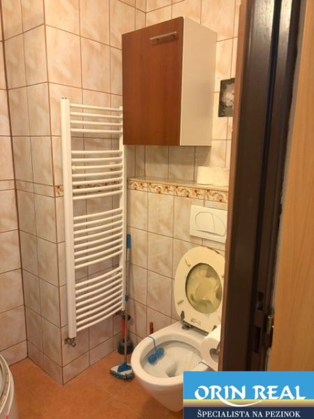 Bathroom in a studio apartment with tiles and a radiator.