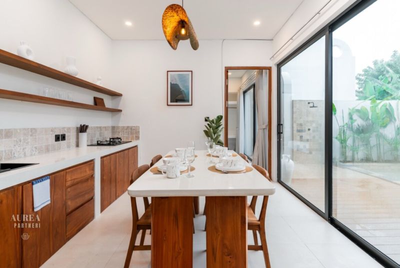 Dining room in a villa with wooden decor, set table and large window to the terrace.
