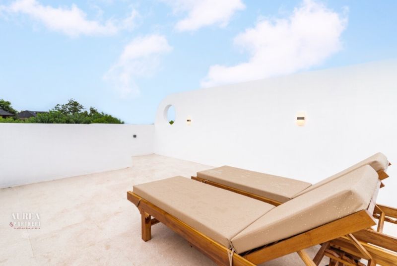 Sun loungers on the terrace of a villa in Bali under a blue sky.