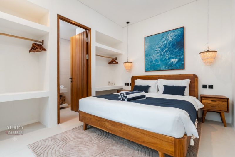 Bright bedroom in a villa with wooden furniture and a painting above the bed.