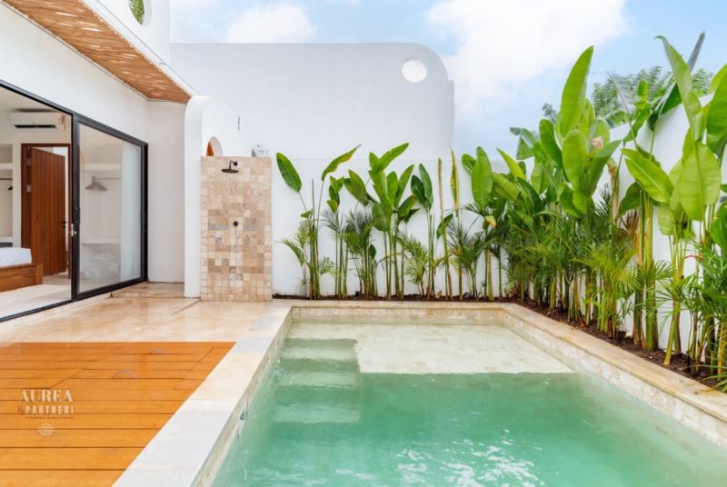 Villa in Bali with a pool, tropical plants, and wooden decor flooring.