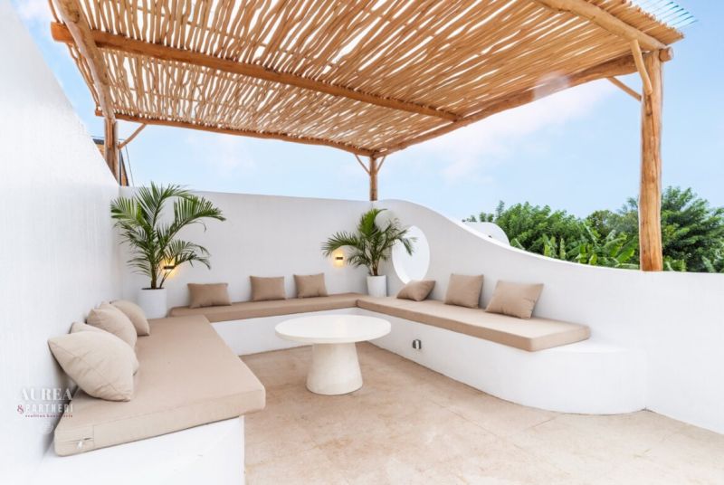 A villa with a terrace and white seating surrounded by green plants in Bali.