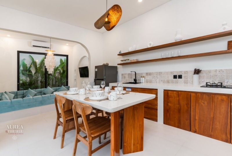 The kitchen in the villa with a dining table, wooden furniture, and a view of the garden.