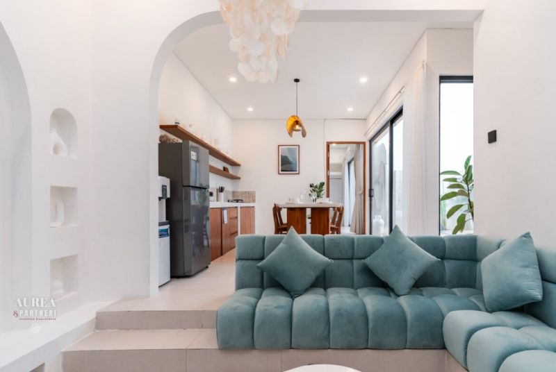 Living room in a villa with a turquoise sofa, dining table, and wooden decor.