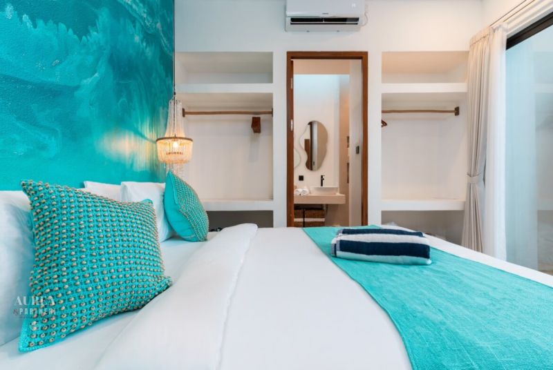 A bedroom in a villa with turquoise details and an entrance to the bathroom.