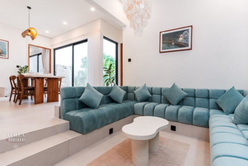 Living room in a villa with a turquoise sofa and a wooden dining table.