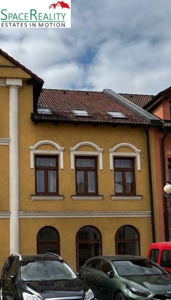 A building in Topoľčany with a historical facade and parked cars in front of it.