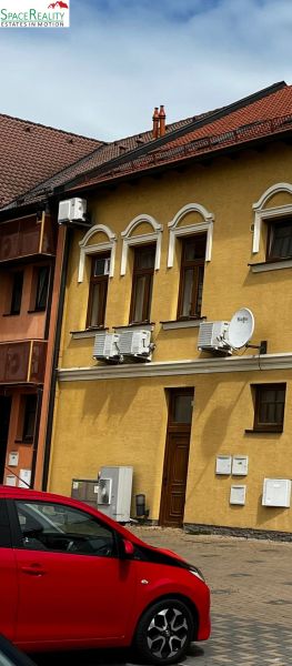 Yellow historical building in Topoľčany with air conditioning units and a satellite dish.