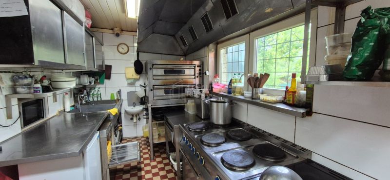 A kitchen in commercial premises with appliances and stainless steel counters.