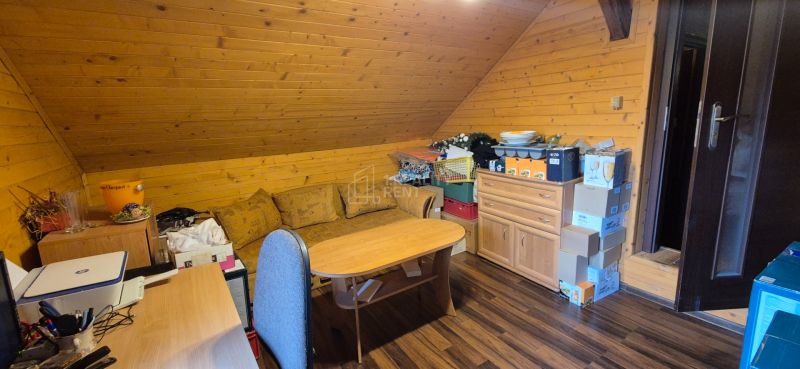 Attic interior with a sofa, table, and wooden decor flooring in commercial premises.