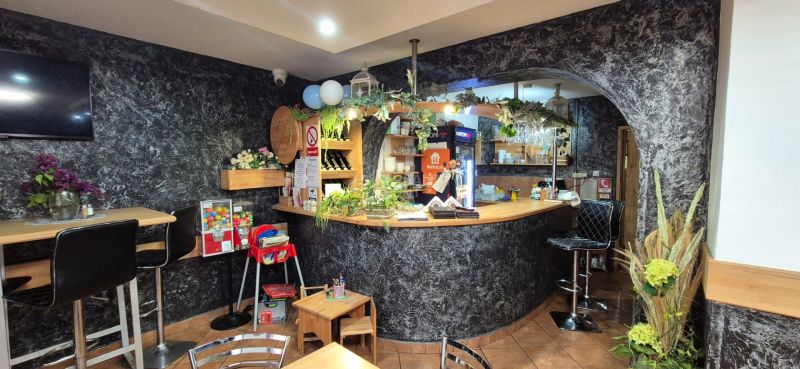 Interior of commercial premises with a bar counter, flowers, and a children's corner.