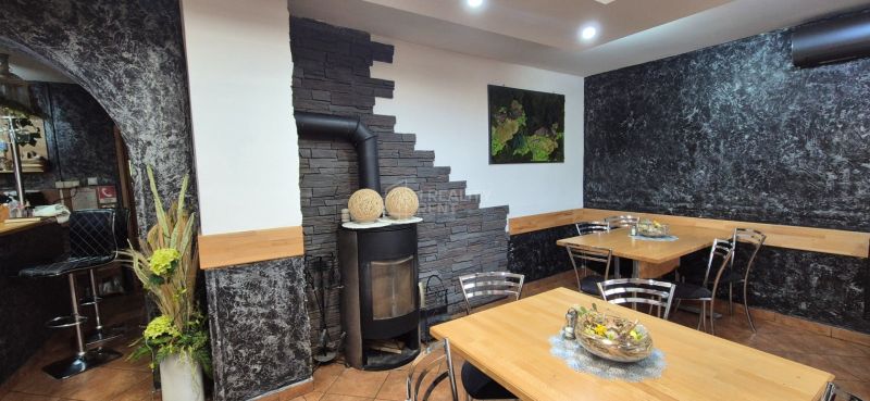 Commercial space with a wood-burning stove, wooden tables, and floral decorations on the walls.