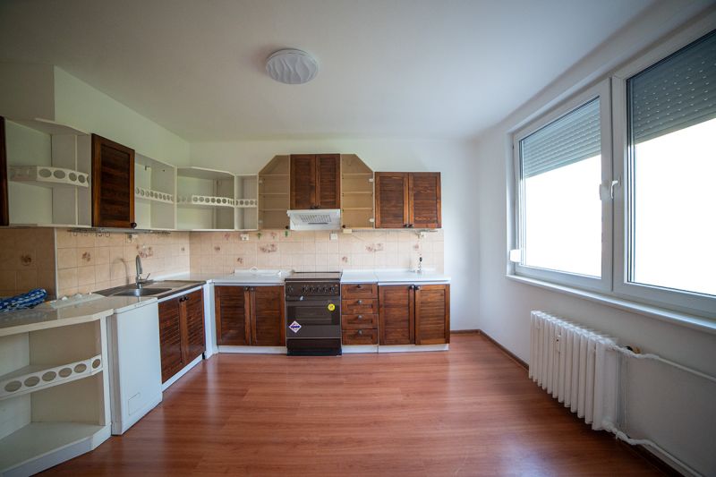 A kitchen in a 2-room apartment with a wooden decor floor and wooden cabinets.