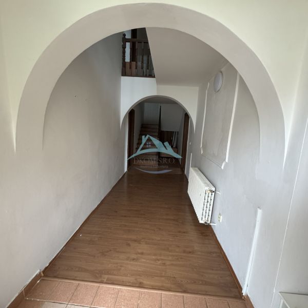 Interior of a family house with arches and wood-patterned flooring.