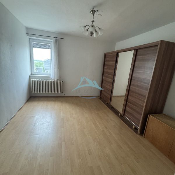 A room with a wooden floor decor, a wardrobe, and a window in a family house.