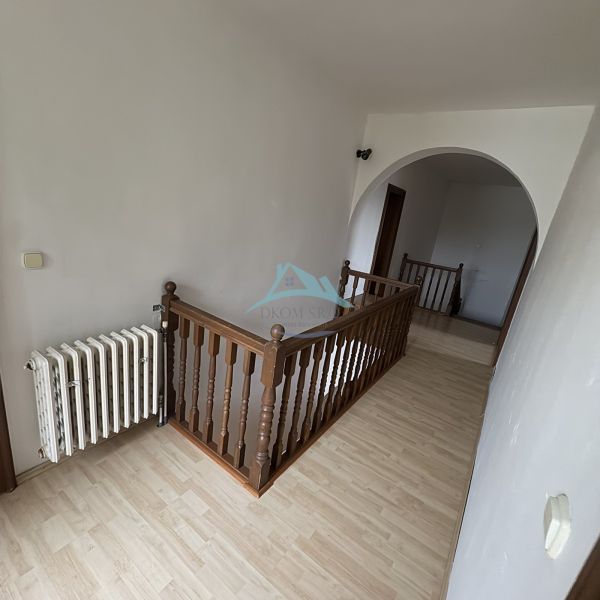 A hallway in a family house with a wooden decor floor and wooden railing.