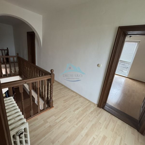 A staircase with a wooden railing and a floor with a wooden decor in a family house.