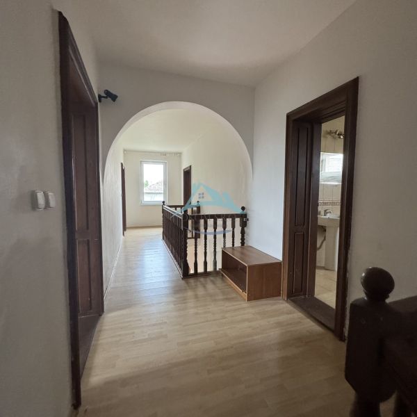 Hallway in a family house with a wood-patterned floor and wooden railing.