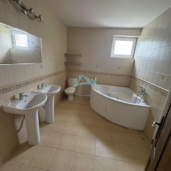 A bathroom in a family house with two sinks and a corner bathtub.