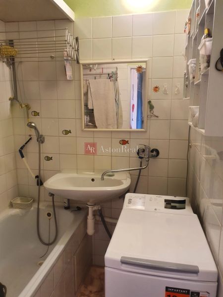 Bathroom with a bathtub, sink, and washing machine in a 3-room apartment.
