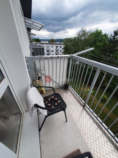 A balcony with a view of greenery and apartment buildings on Nábrežná Street in Trenčín.