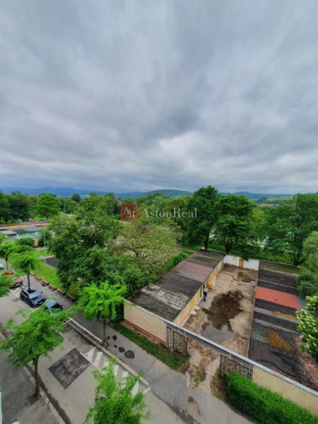 A view from above of Nábrežná Street, Trenčín, with garages and greenery near a 3-room apartment.