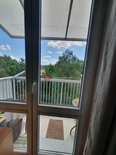View from a 3-room apartment to a balcony overlooking greenery and clouds.