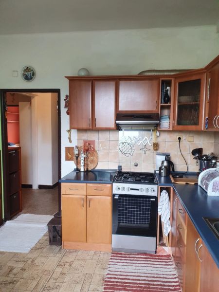 A kitchen in a 3-room apartment with a gas stove, wooden cabinets, and a floor with a decor.