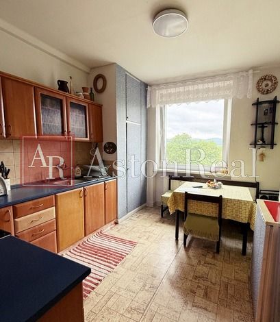 A kitchen in a 3-room apartment with a wooden decor floor and light furniture.