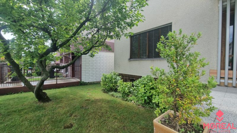 A garden by a family house in Leopoldov with dense bushes and a tree in the green lawn.